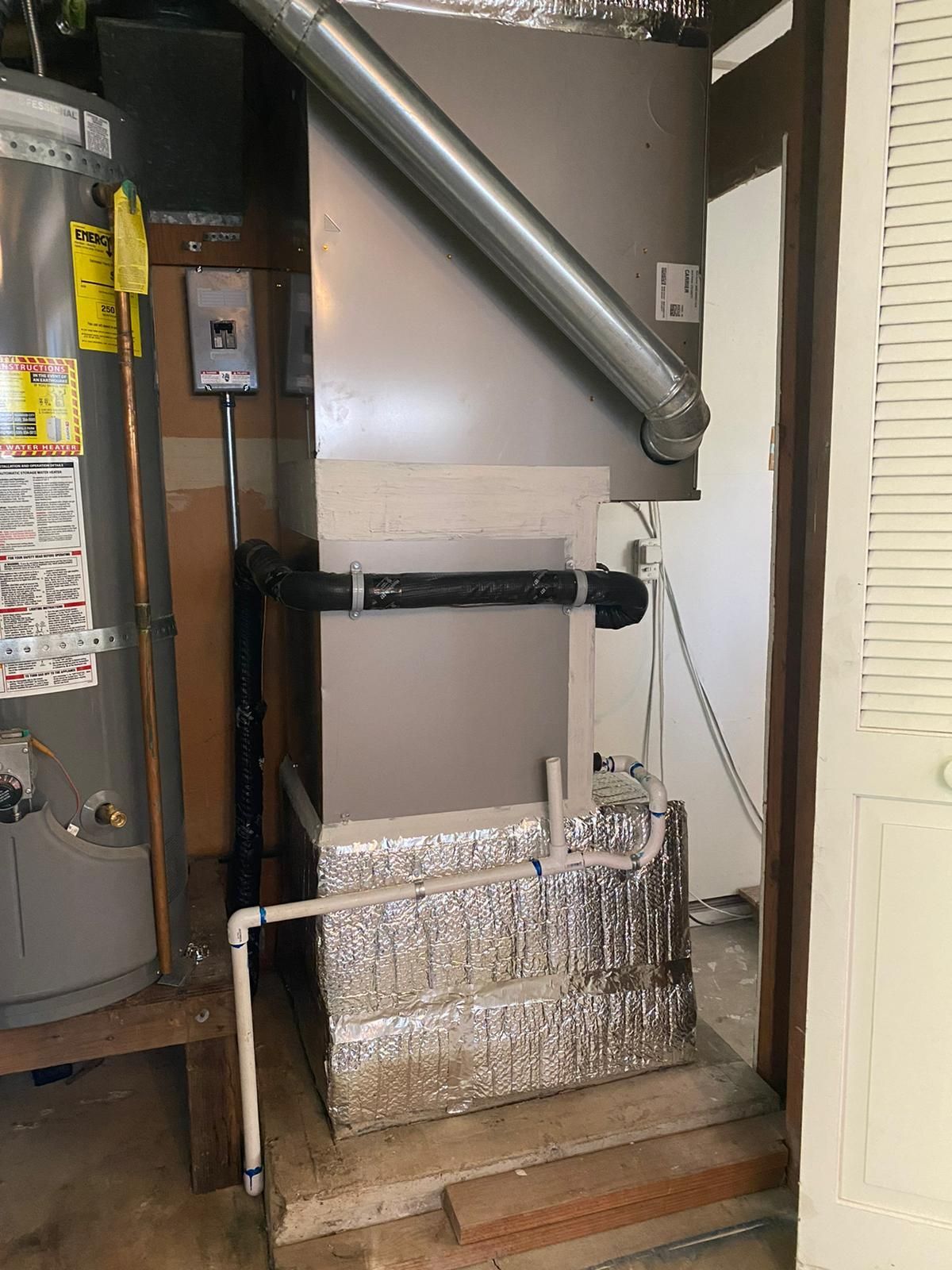 An air conditioner is sitting in a room next to a water heater.