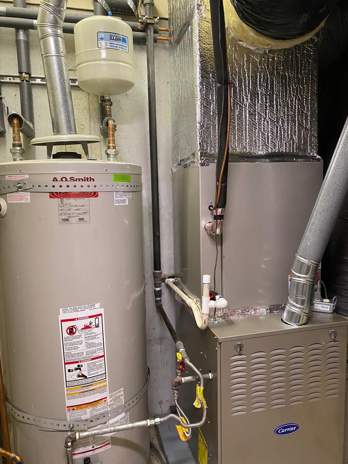 A water heater is sitting next to an air conditioner in a room.
