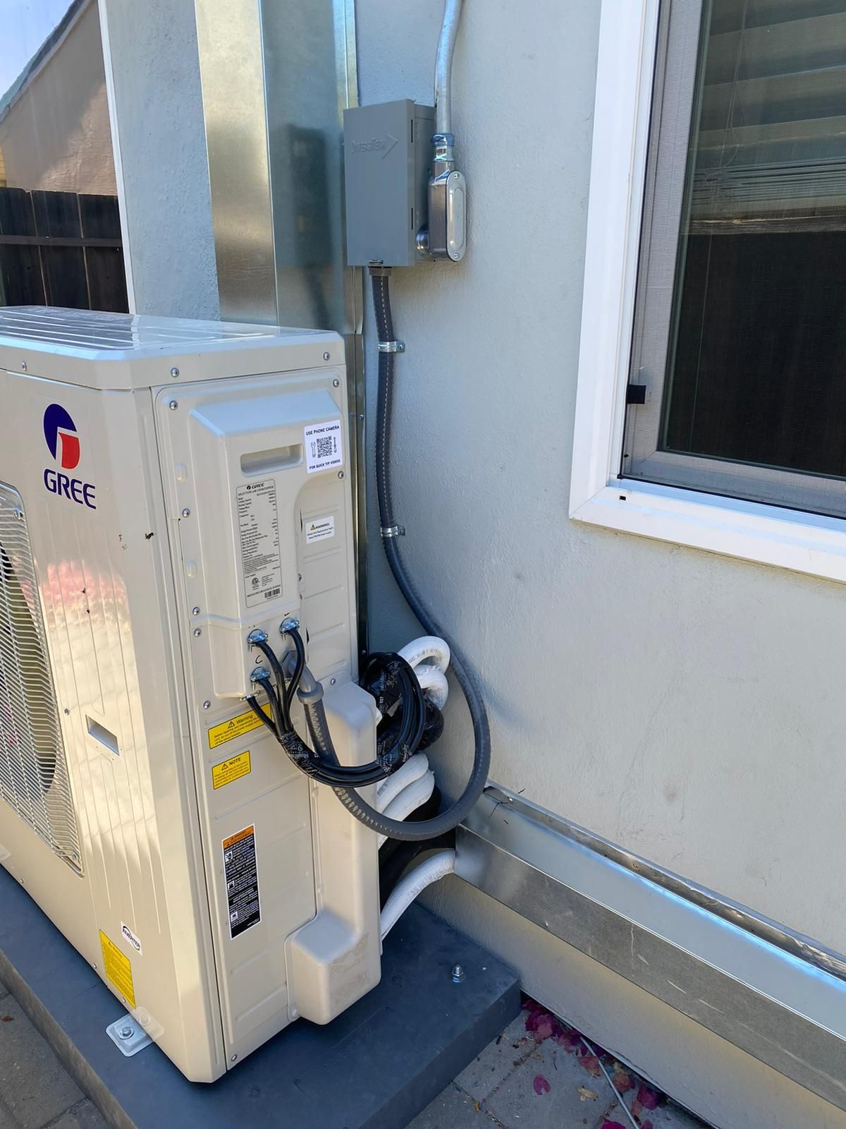 A large air conditioner is sitting on the side of a building next to a window.