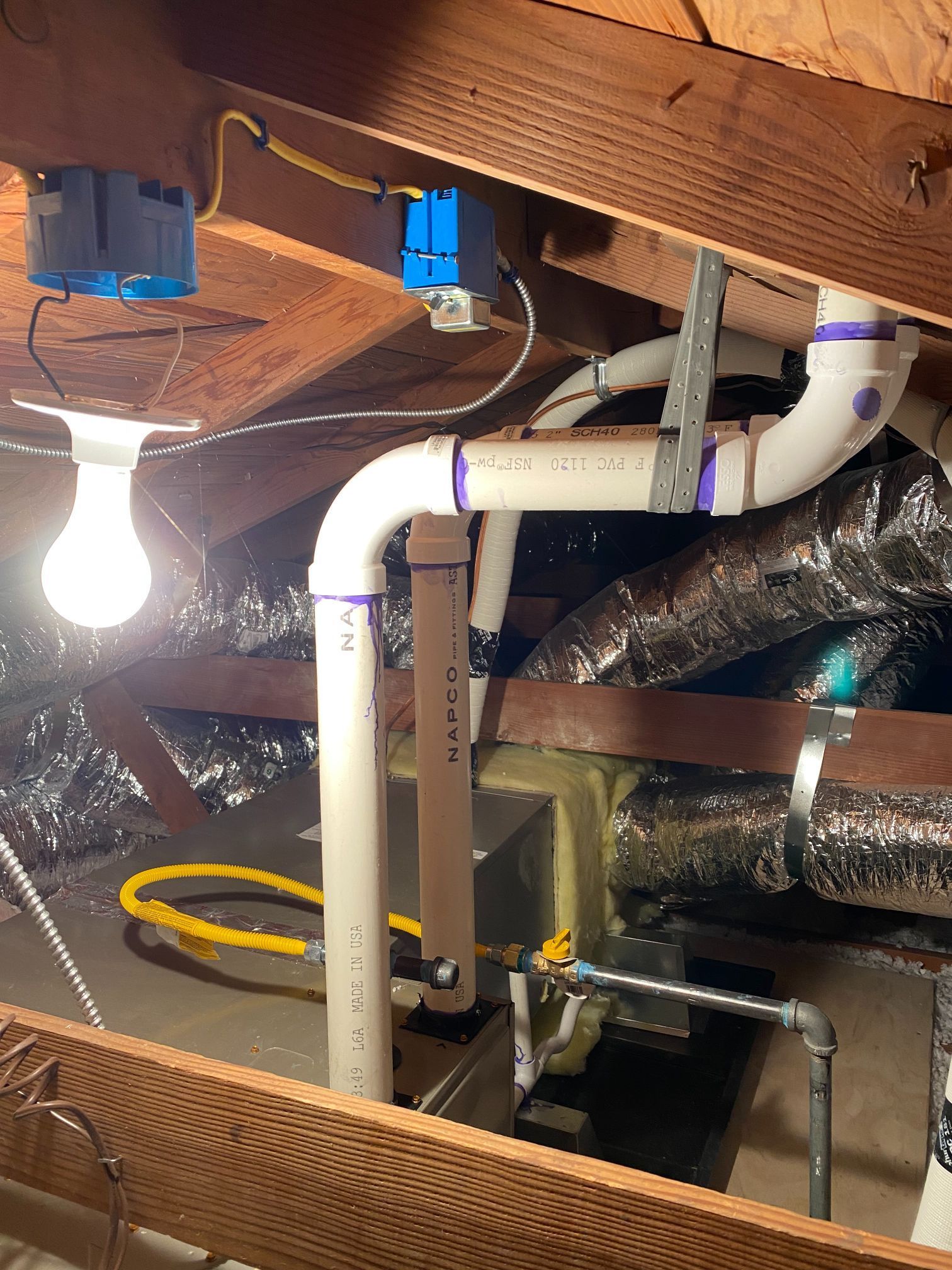 There is a light bulb hanging from the ceiling in the attic.