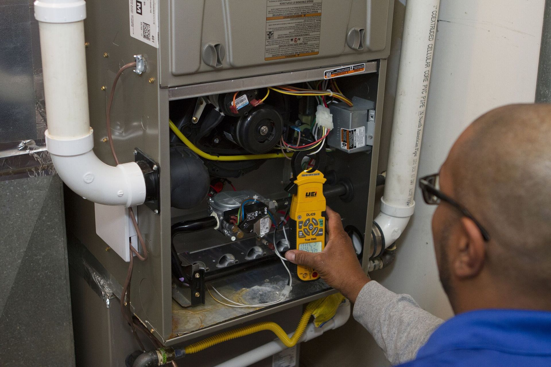 A man is working on an air conditioner with a thermometer in his hand.