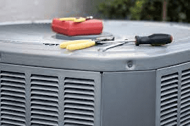 A close up of an air conditioner with tools on top of it.