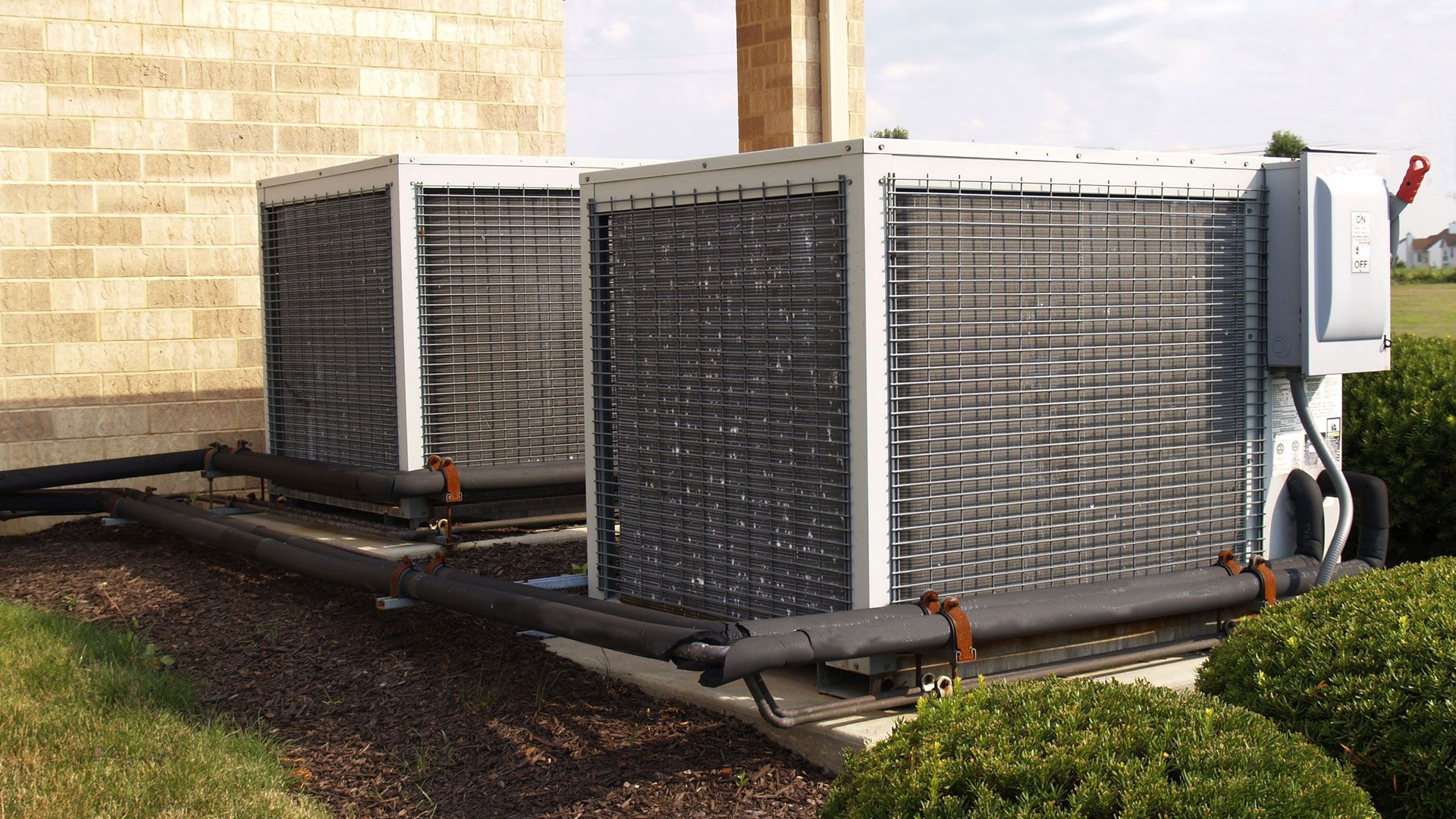 Two air conditioners are sitting on the side of a building.