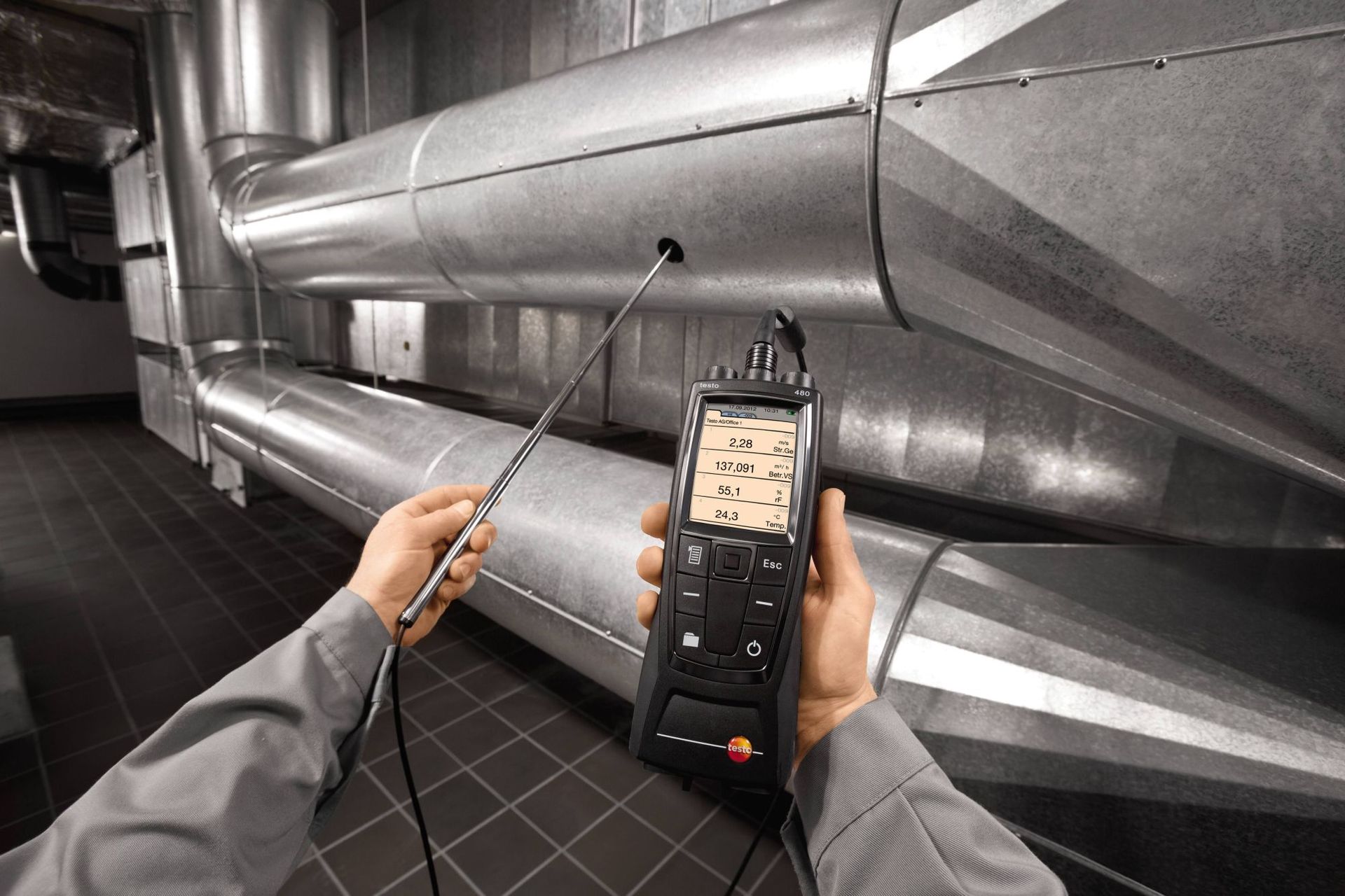 A person is using a thermometer to measure the temperature of a pipe.