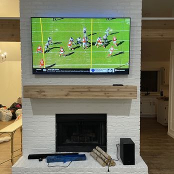 A flat screen tv is hanging over a fireplace in a living room.