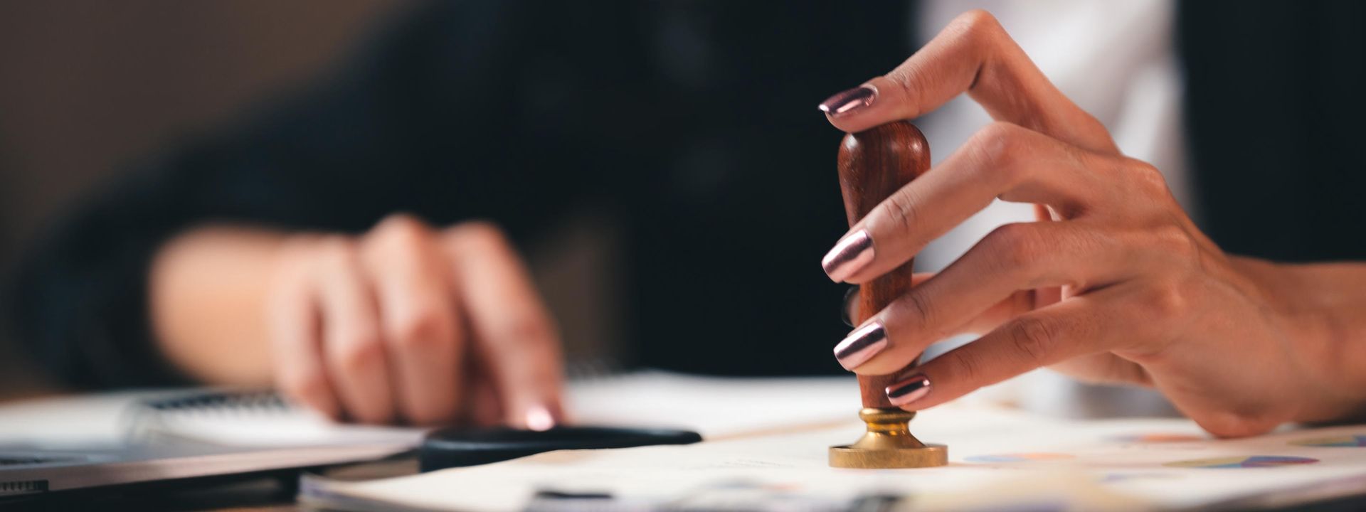 A woman is stamping a document with a wax seal.