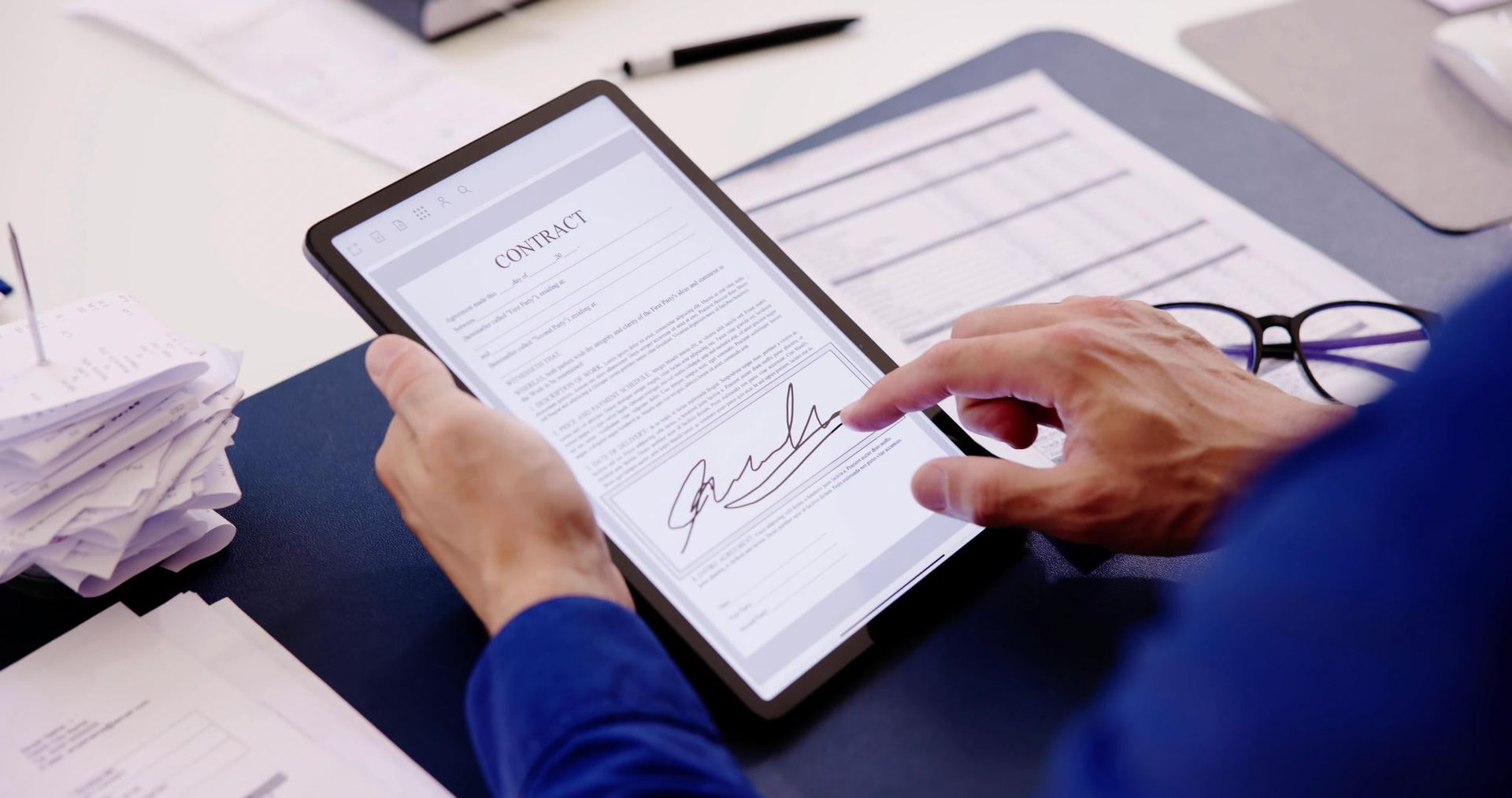 A person is signing a document on a tablet.