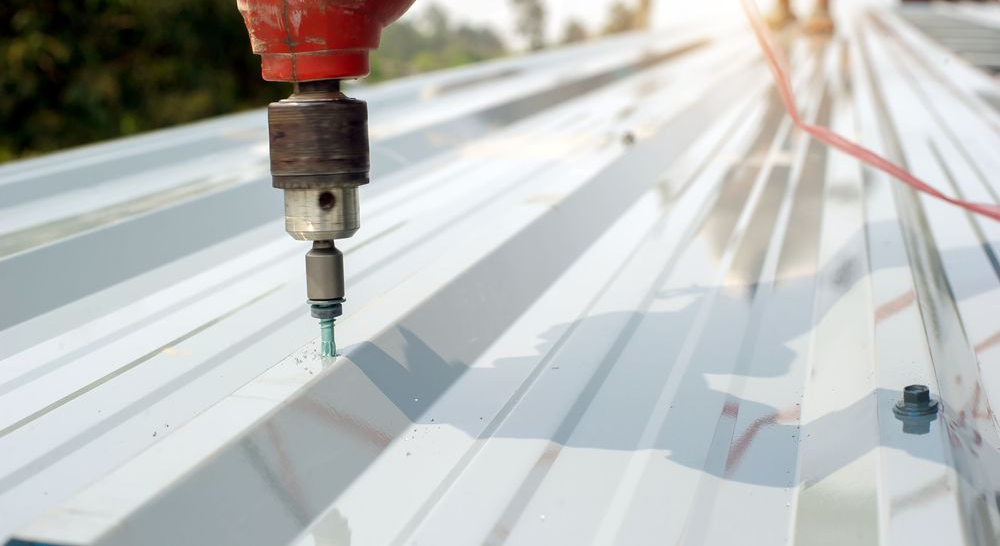 Person Using a Red Drill to Install Metal Roofing — Blue Sky Roofing NSW In Bangalow, NSW