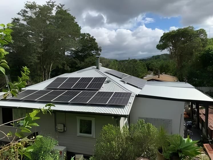 Solar Panels on a House Roof in a Lush Green Setting With a Cloudy Sky — Blue Sky Roofing NSW In Mullumbimby, NSW