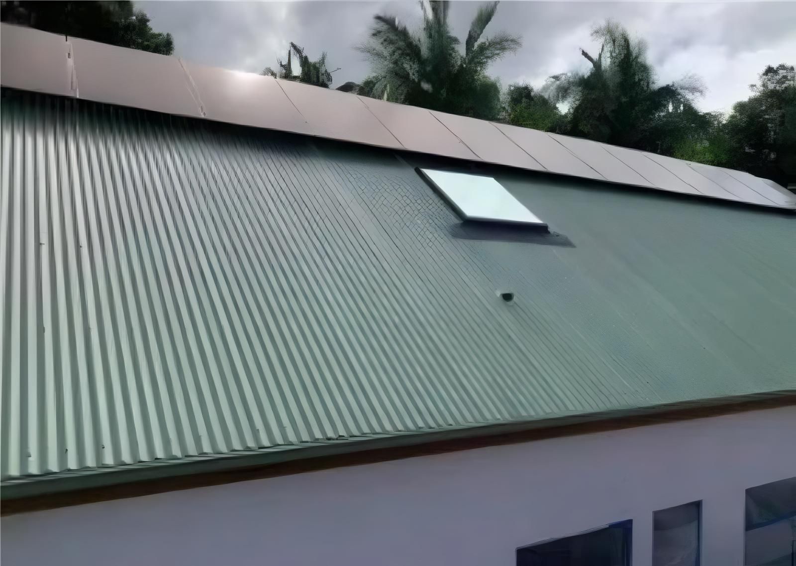 Green Corrugated Metal Roof With Solar Panels and a Skylight — Blue Sky Roofing NSW In Ocean Shores, NSW