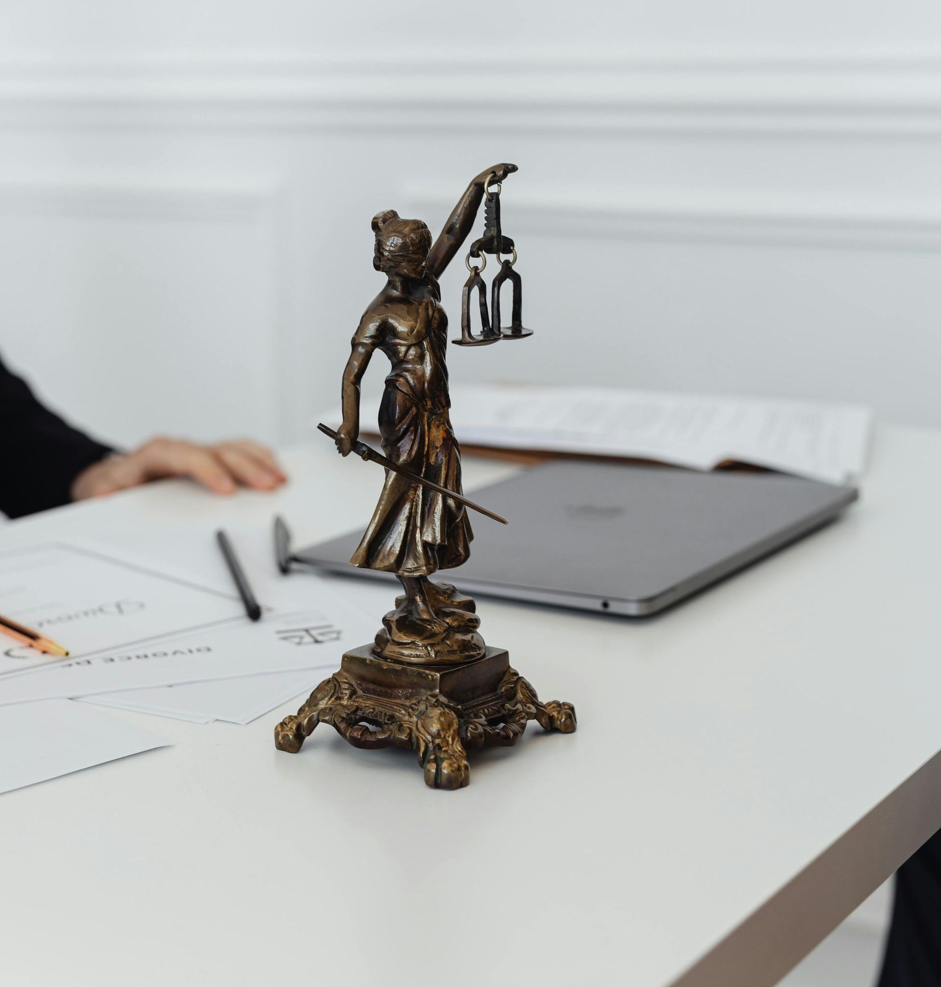 A statue of justice is sitting on a table next to a laptop.