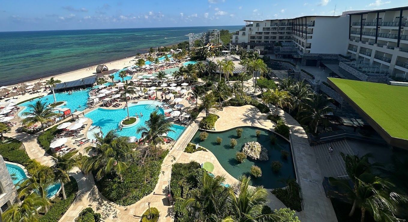 An aerial view of a large resort with swimming pools and a beach.