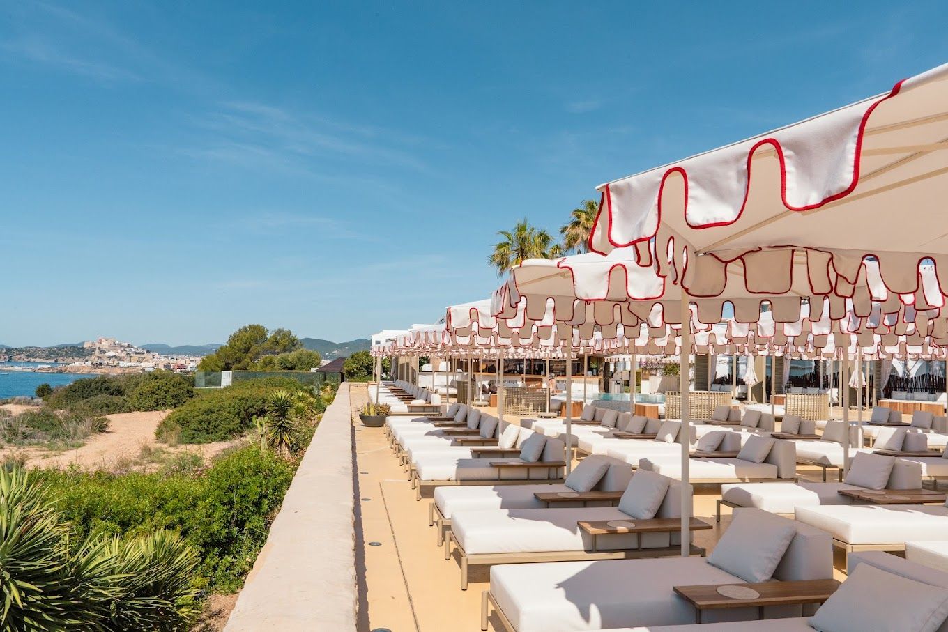 A row of lounge chairs and umbrellas on a rooftop overlooking the ocean.