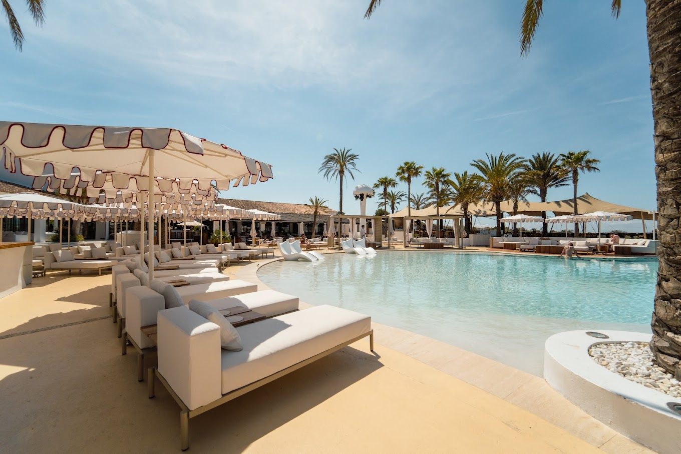 A row of lounge chairs and umbrellas on a rooftop overlooking the ocean.