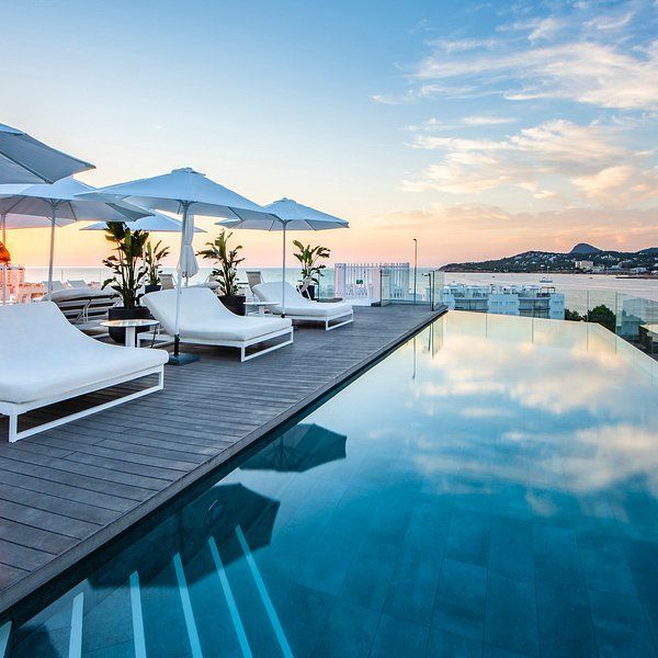 A swimming pool with chairs and umbrellas surrounding it