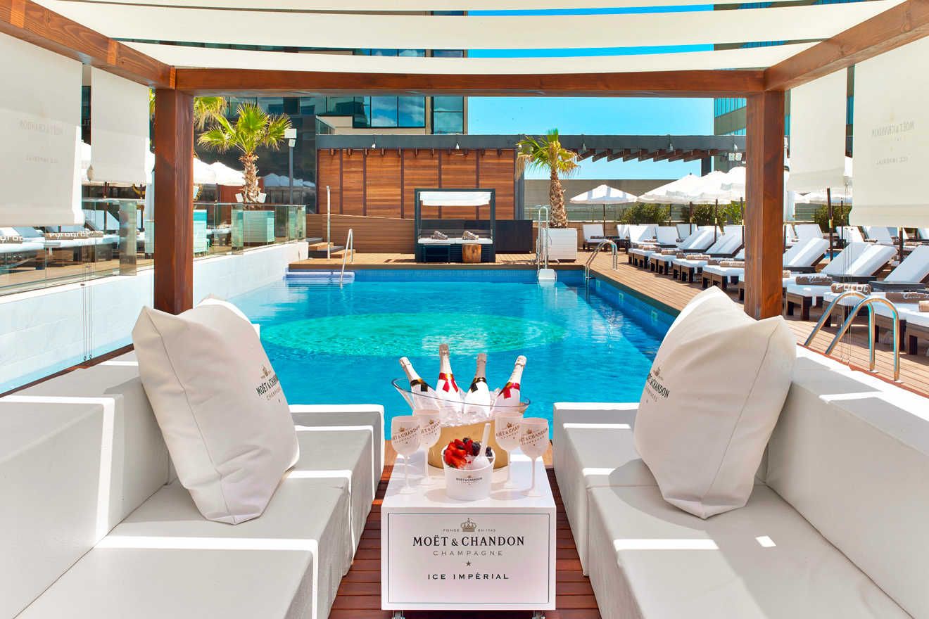 A large swimming pool filled with people at a beach at sunset.