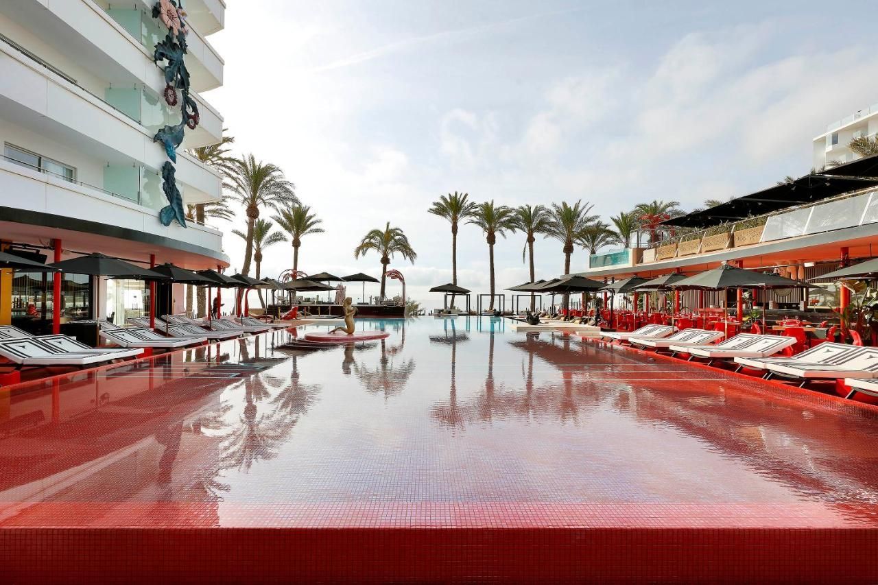 A large swimming pool surrounded by palm trees in a hotel.