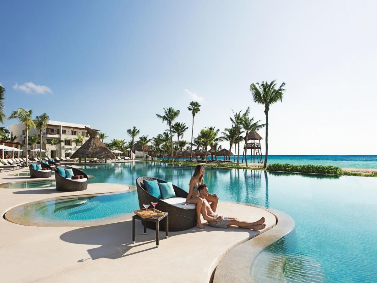 A man and a woman are sitting by a large swimming pool