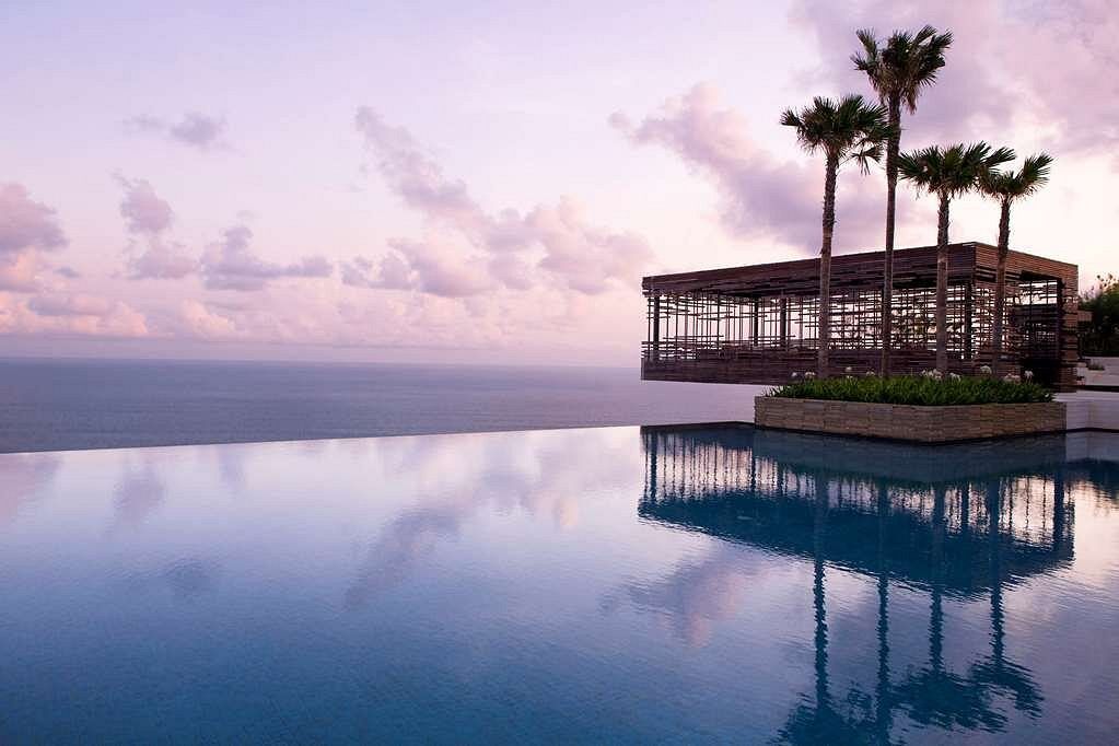 An infinity pool with palm trees and a building in the background