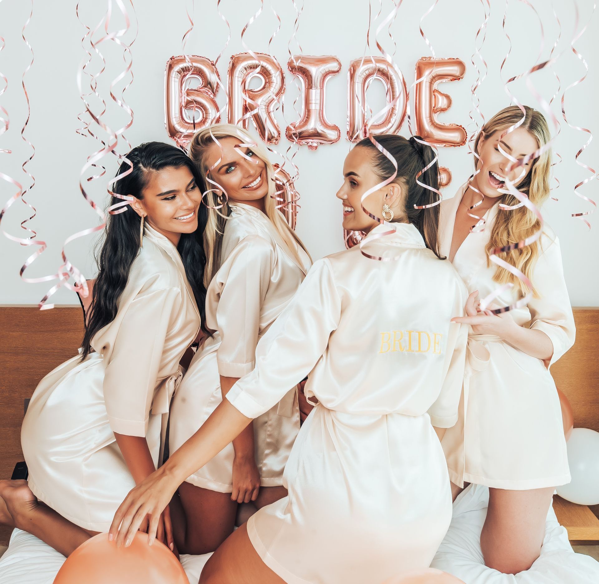 A group of women are posing for a picture in front of a bride balloon.