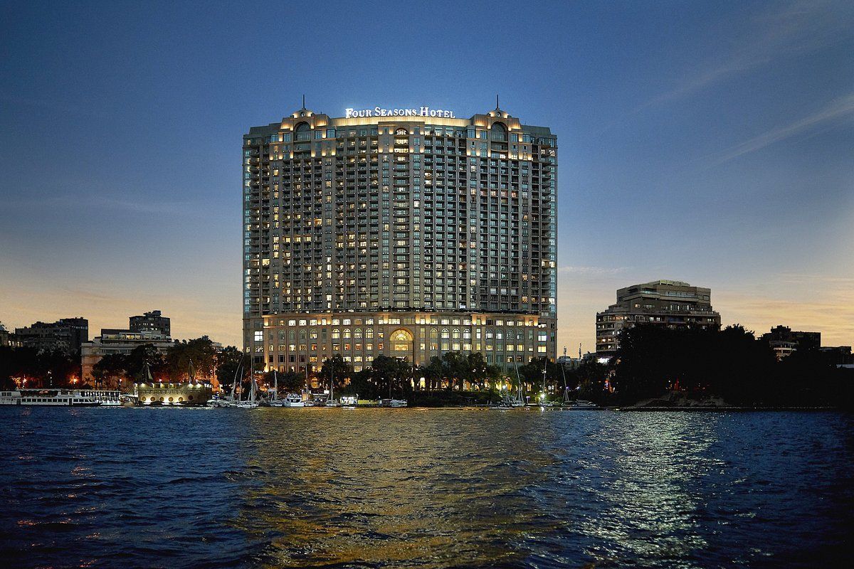 A large building is lit up overlooking a body of water