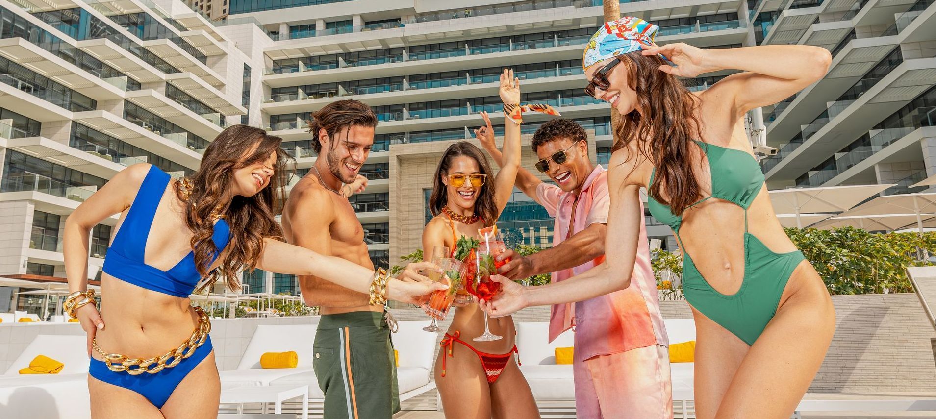 A group of people in bikinis are standing around a pool.