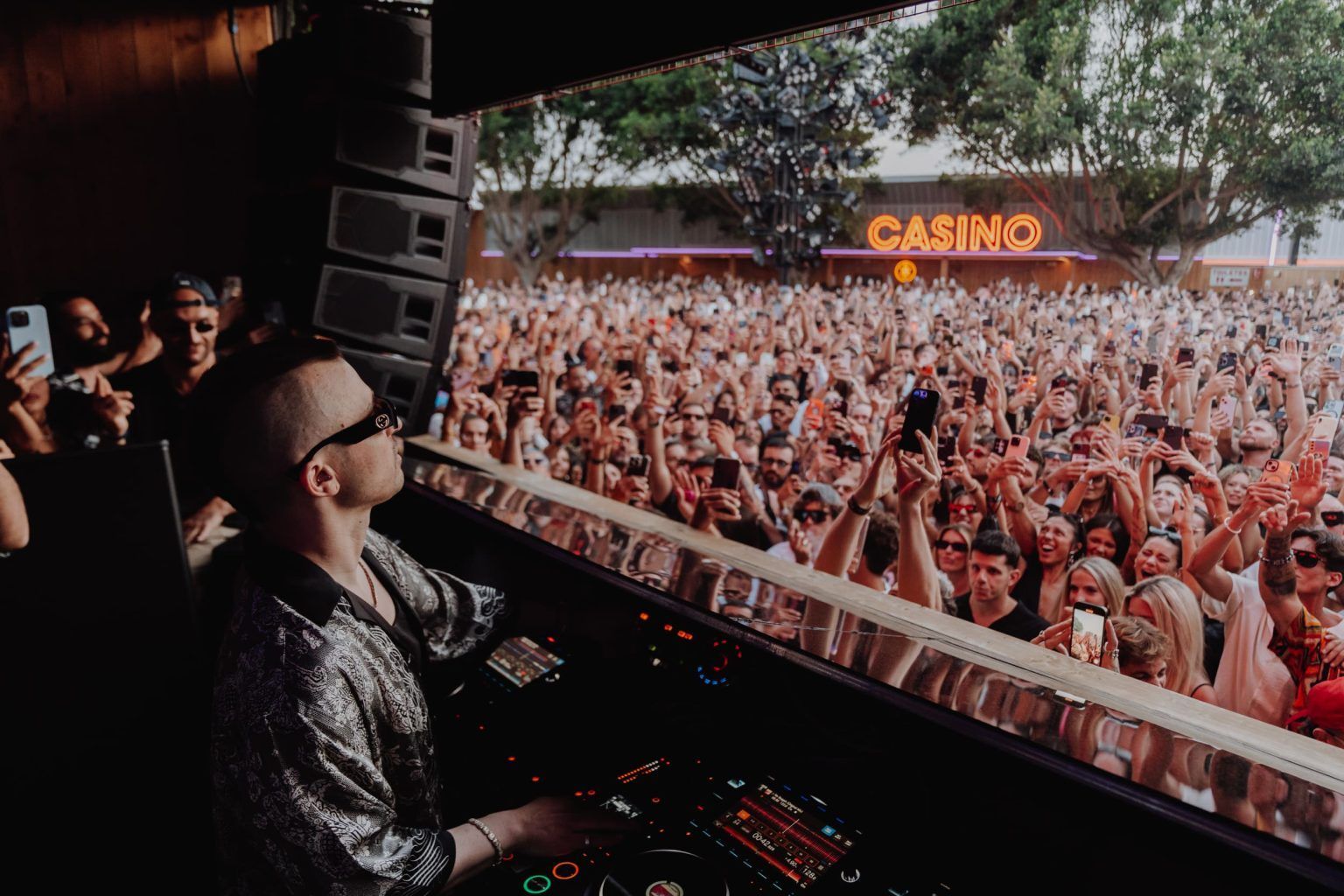 A dj is playing music in front of a crowd at a concert.