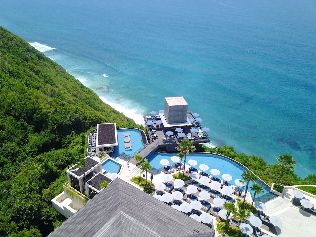 An aerial view of a resort on a cliff overlooking the ocean.