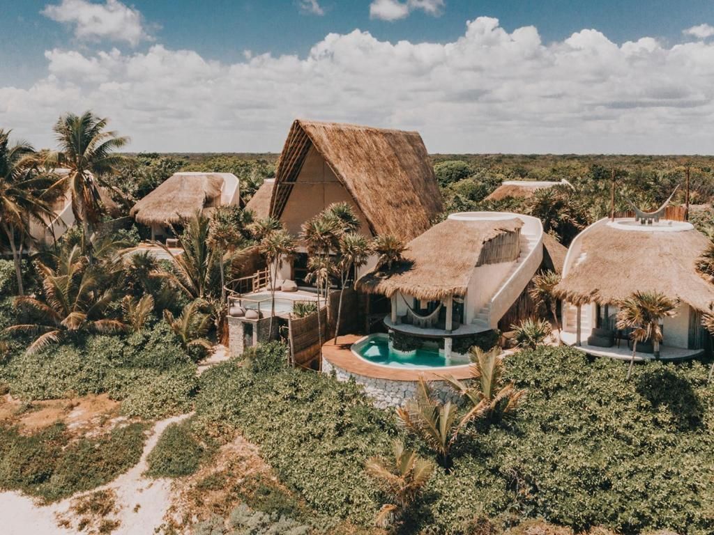 An aerial view of a tropical resort with thatched roofs and a swimming pool.