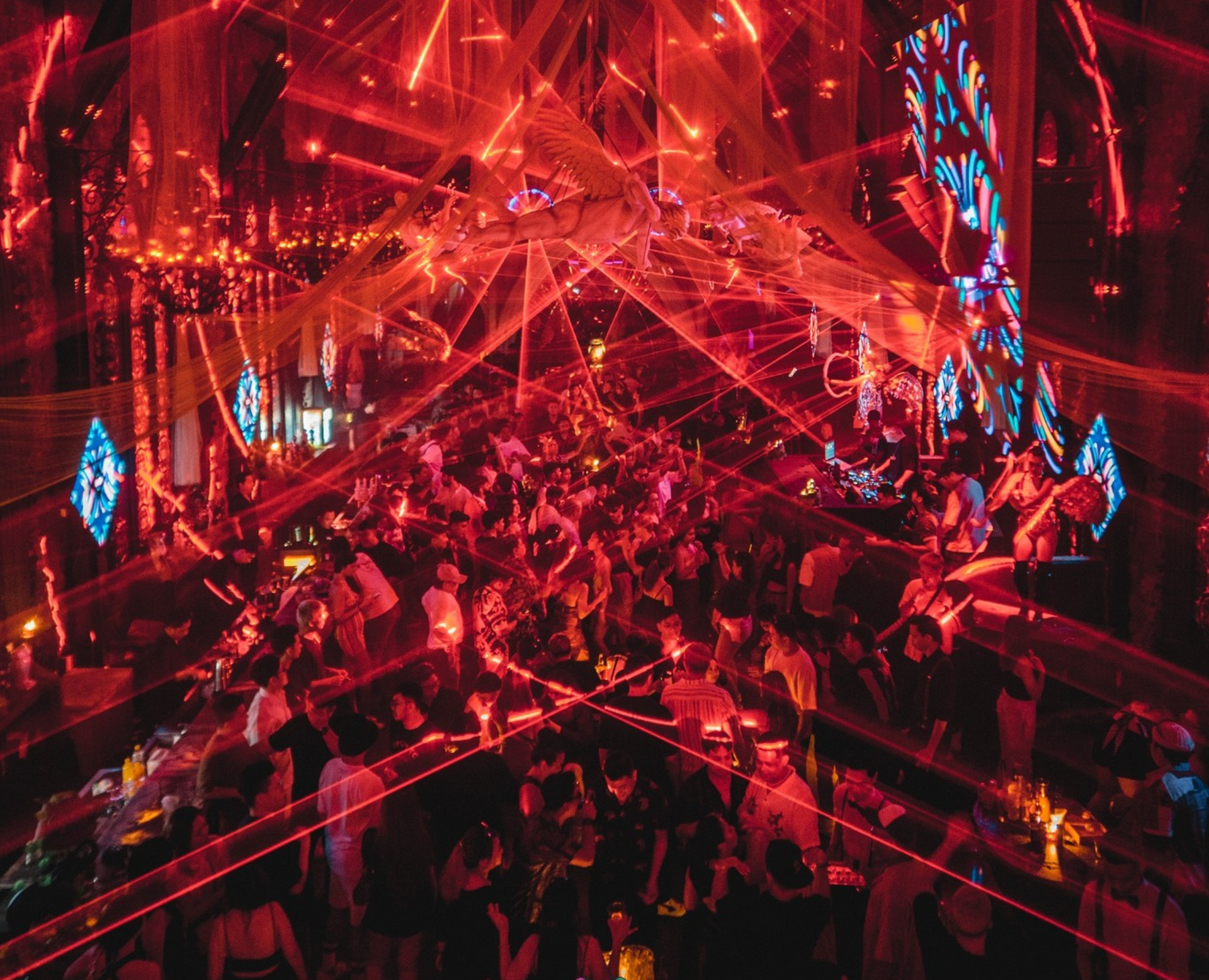 A crowd of people are gathered in a dark room with red lights.