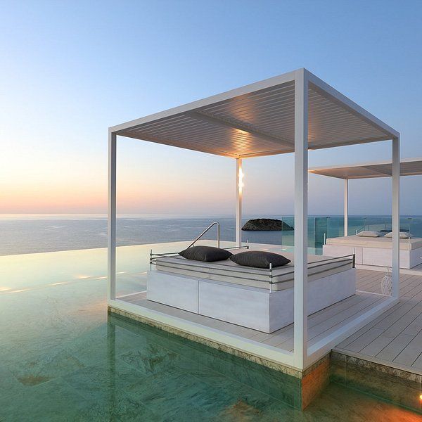 A canopy bed sits in the middle of a swimming pool overlooking the ocean