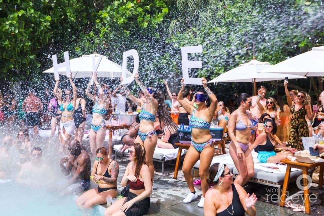 A group of women in bikinis are dancing in a pool at a party.