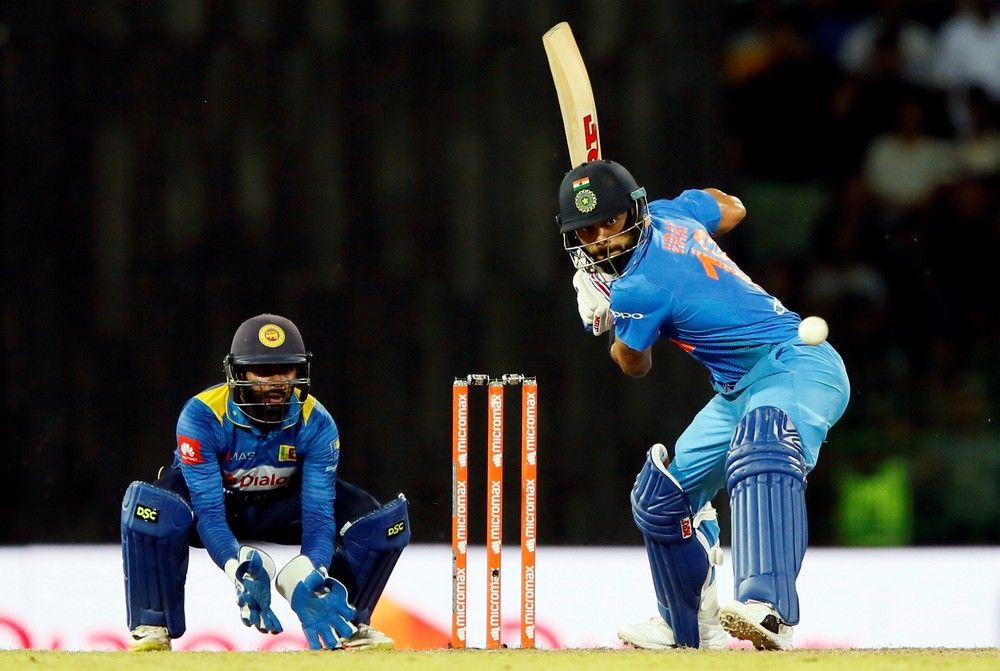 A cricket player is swinging a bat at a ball while another player watches.