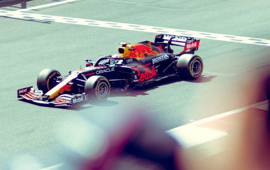 A red bull race car is driving down a race track.