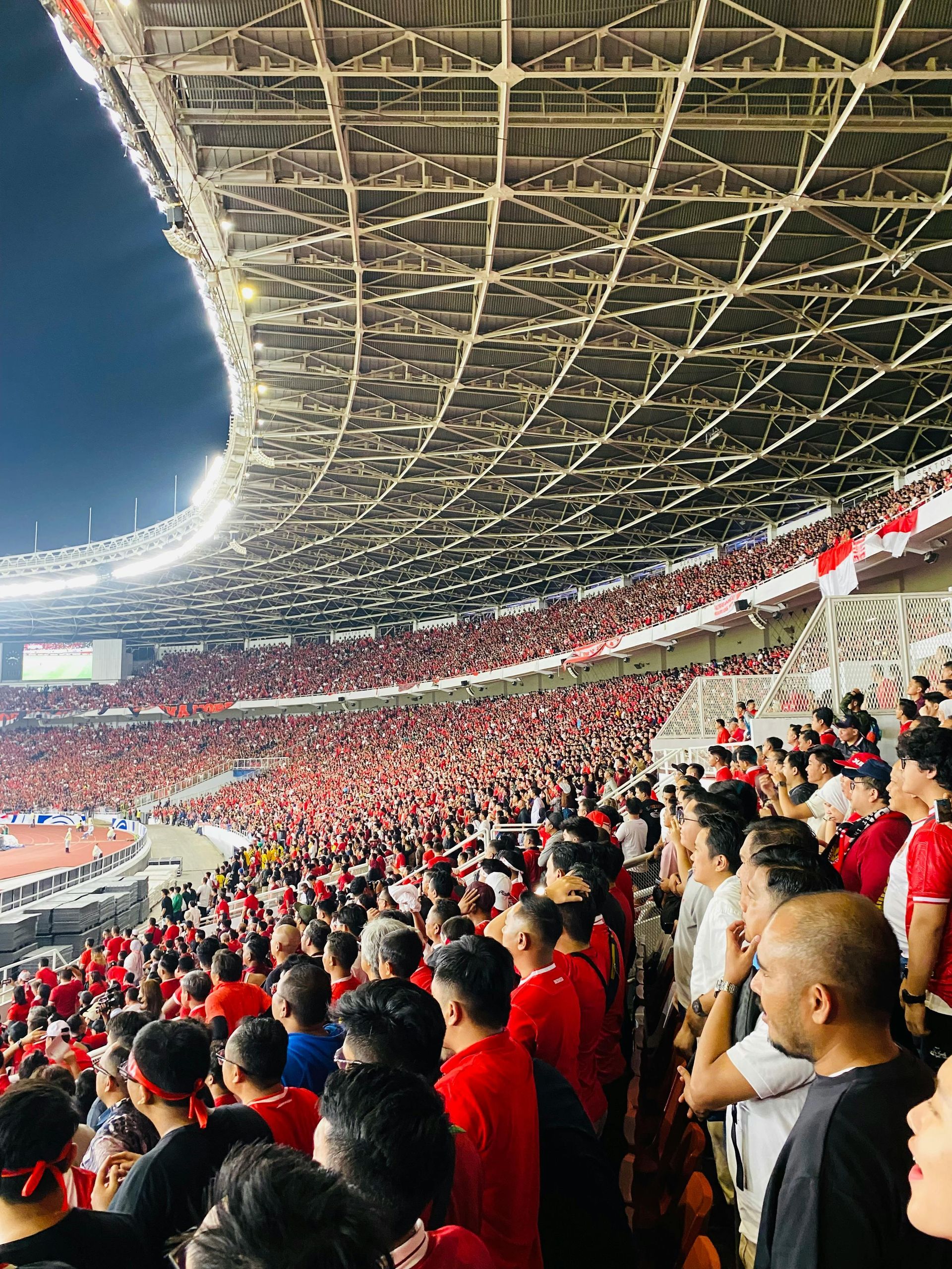 A large crowd of people are watching a soccer game in a stadium.