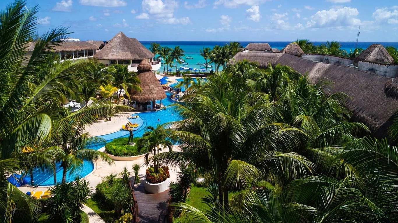 An aerial view of a tropical resort with a large pool surrounded by palm trees.