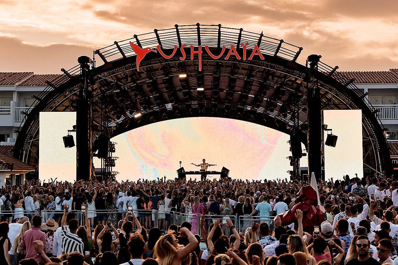 A large crowd of people are standing in front of a stage at a concert.