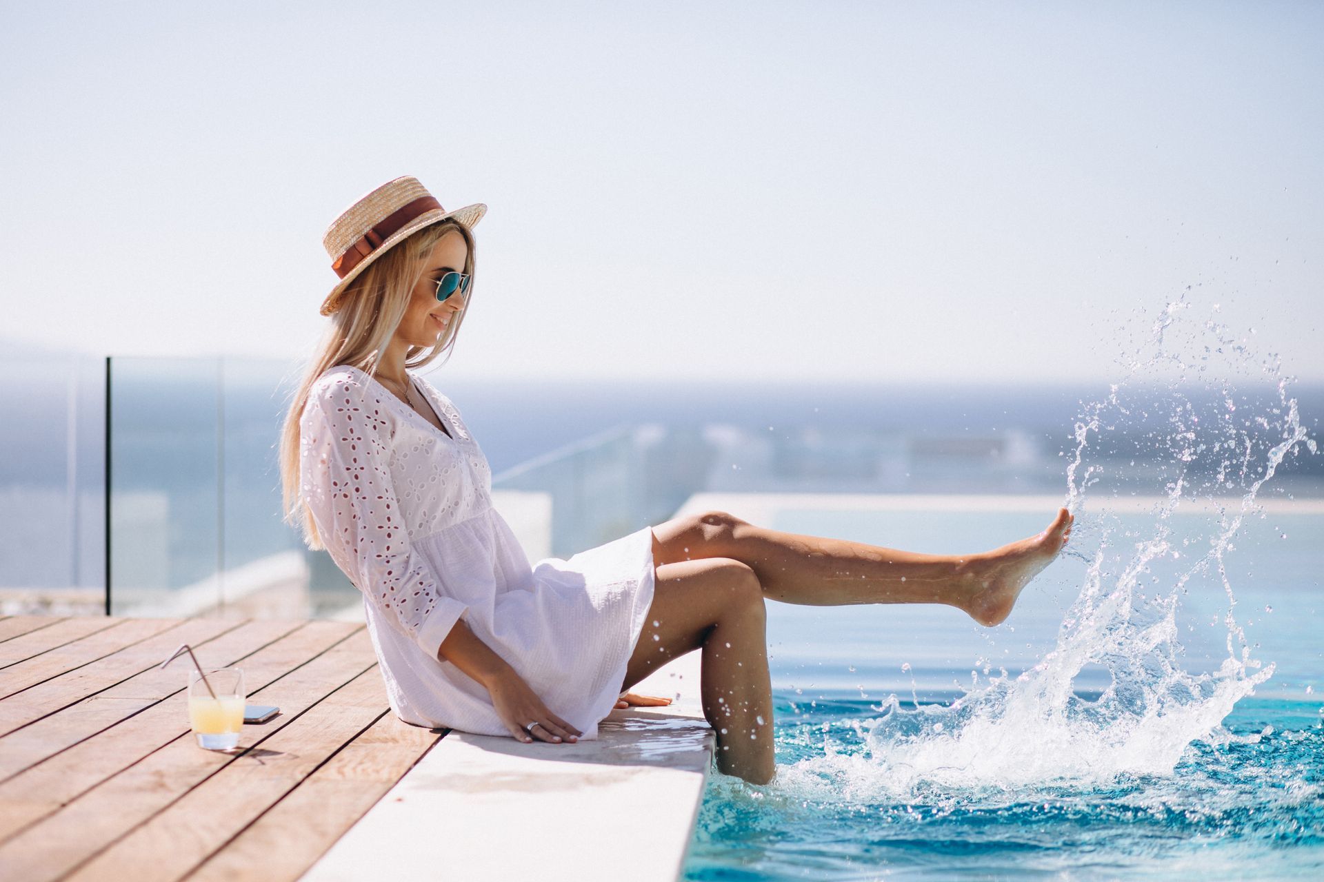A woman is sitting on the edge of a swimming pool with her feet in the water.