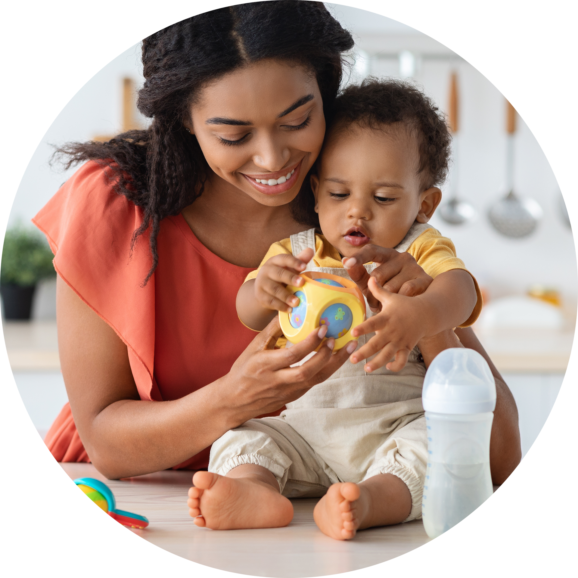 A woman is holding a baby and playing with a toy.