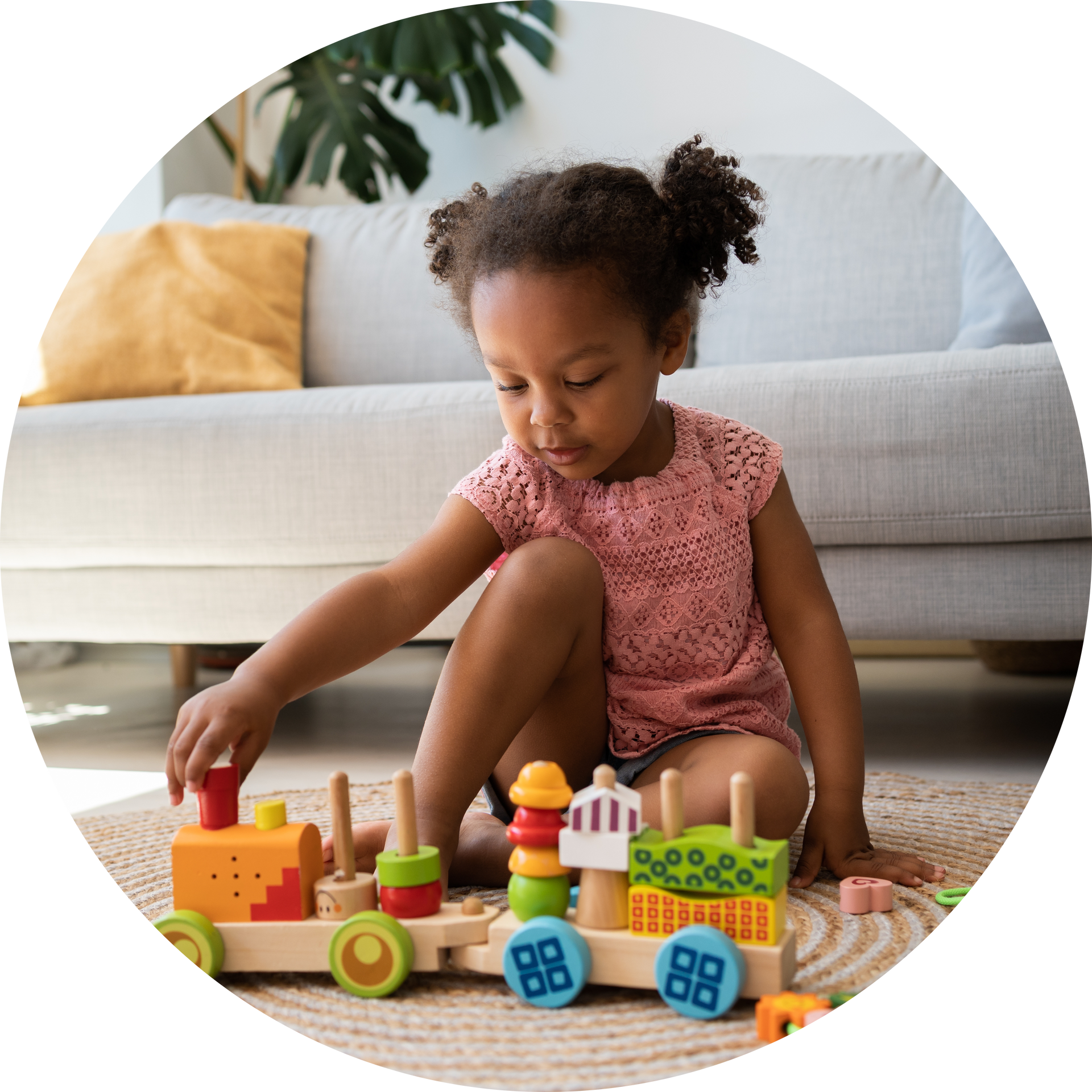 A little girl is sitting on the floor playing with a toy train