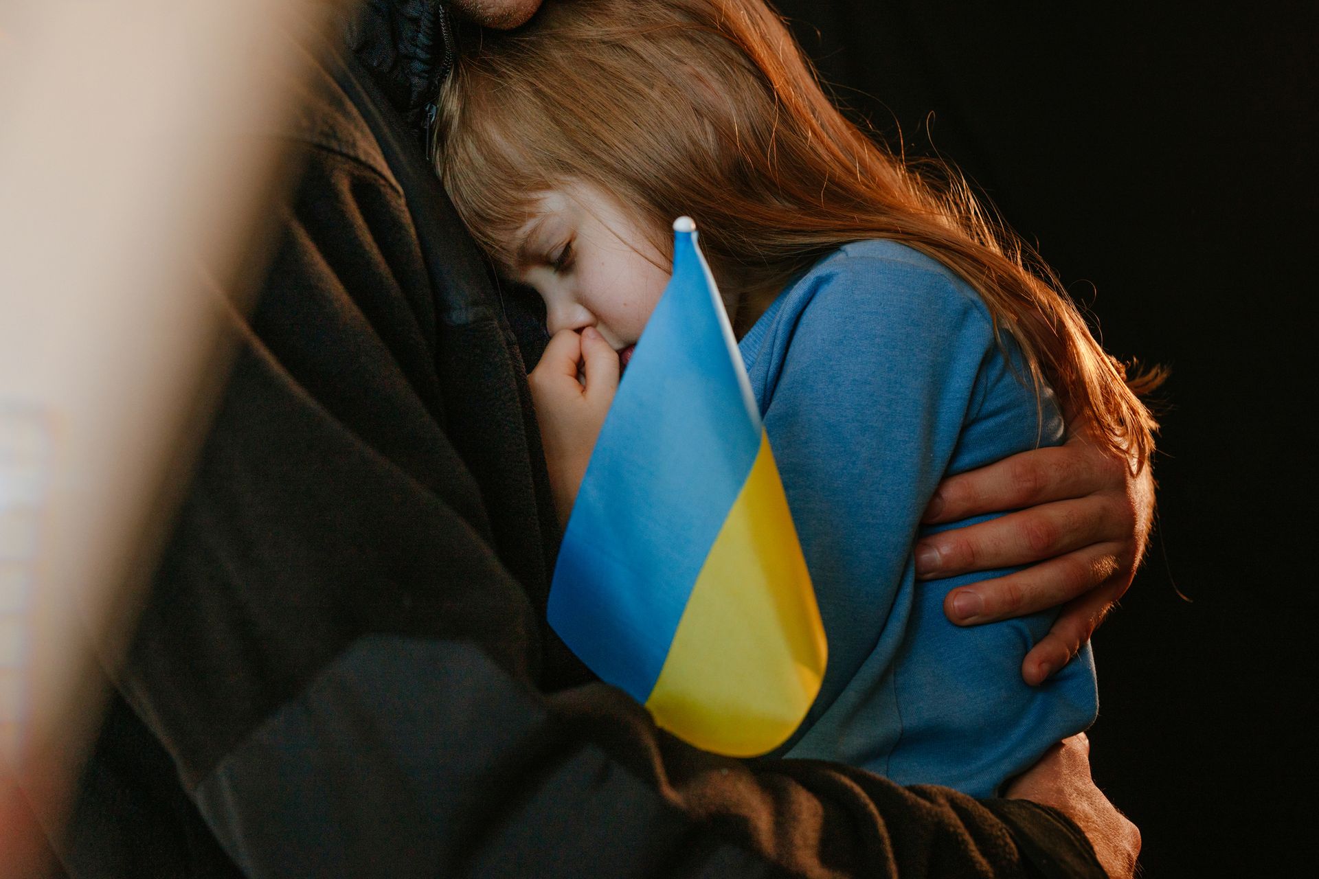 Young girl with Ukrainian flag being held.