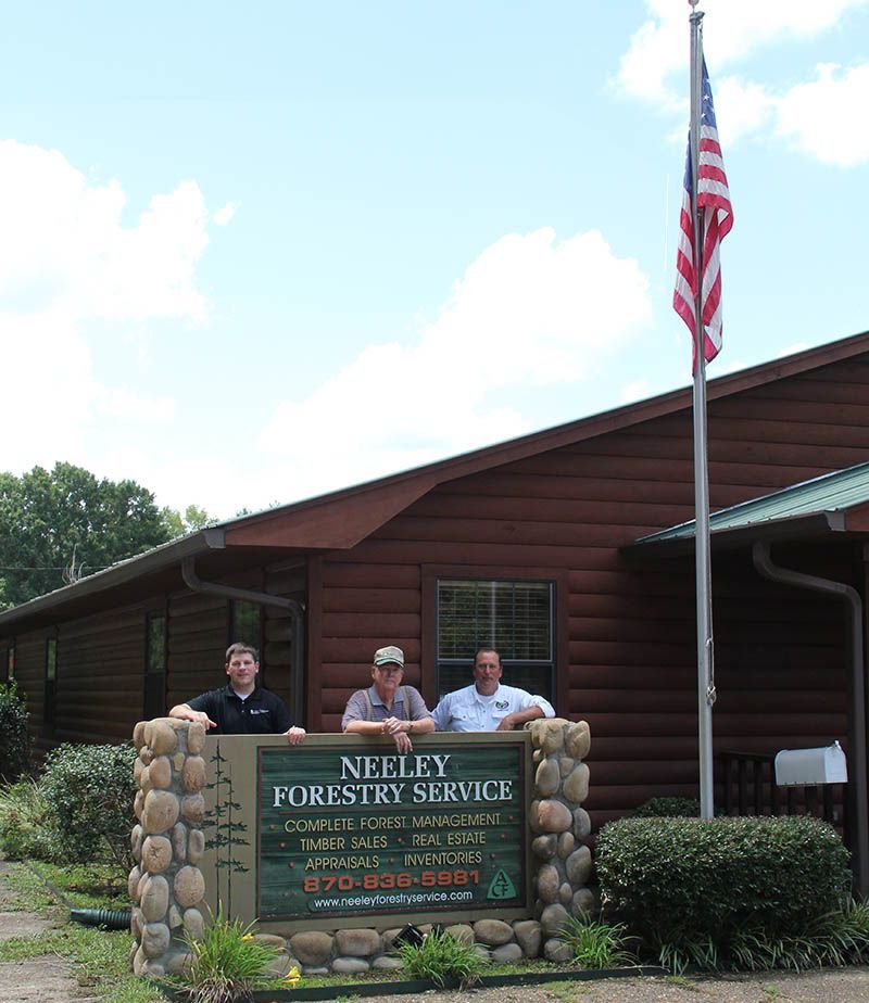 Three men standing in front of a neely forestry service building
