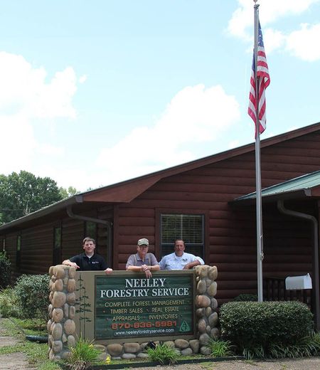 Three men standing in front of a neely forestry service building