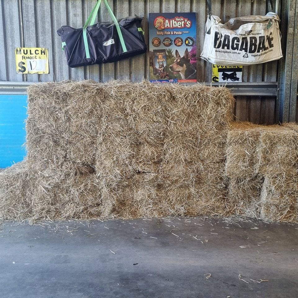 Hay Bales Stacked in a Shed With Price Sign — NQ Stockfeeds & Farm Supplies In Port Douglas, QLD
