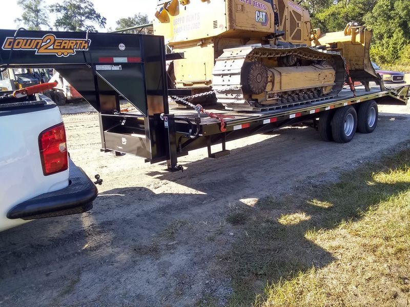 A bulldozer is being towed on a trailer by a white truck