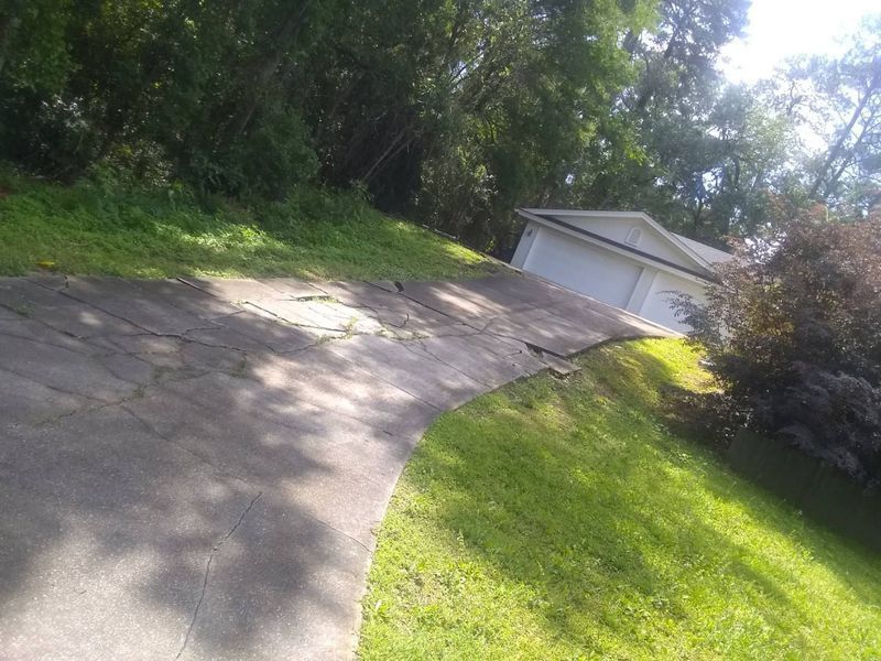A concrete driveway leading to a garage on a hill.