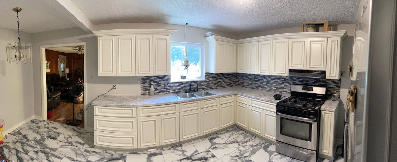 Kitchen remodel with white cabinets, gray countertops, patterned floor, and a black and gray backsplash.