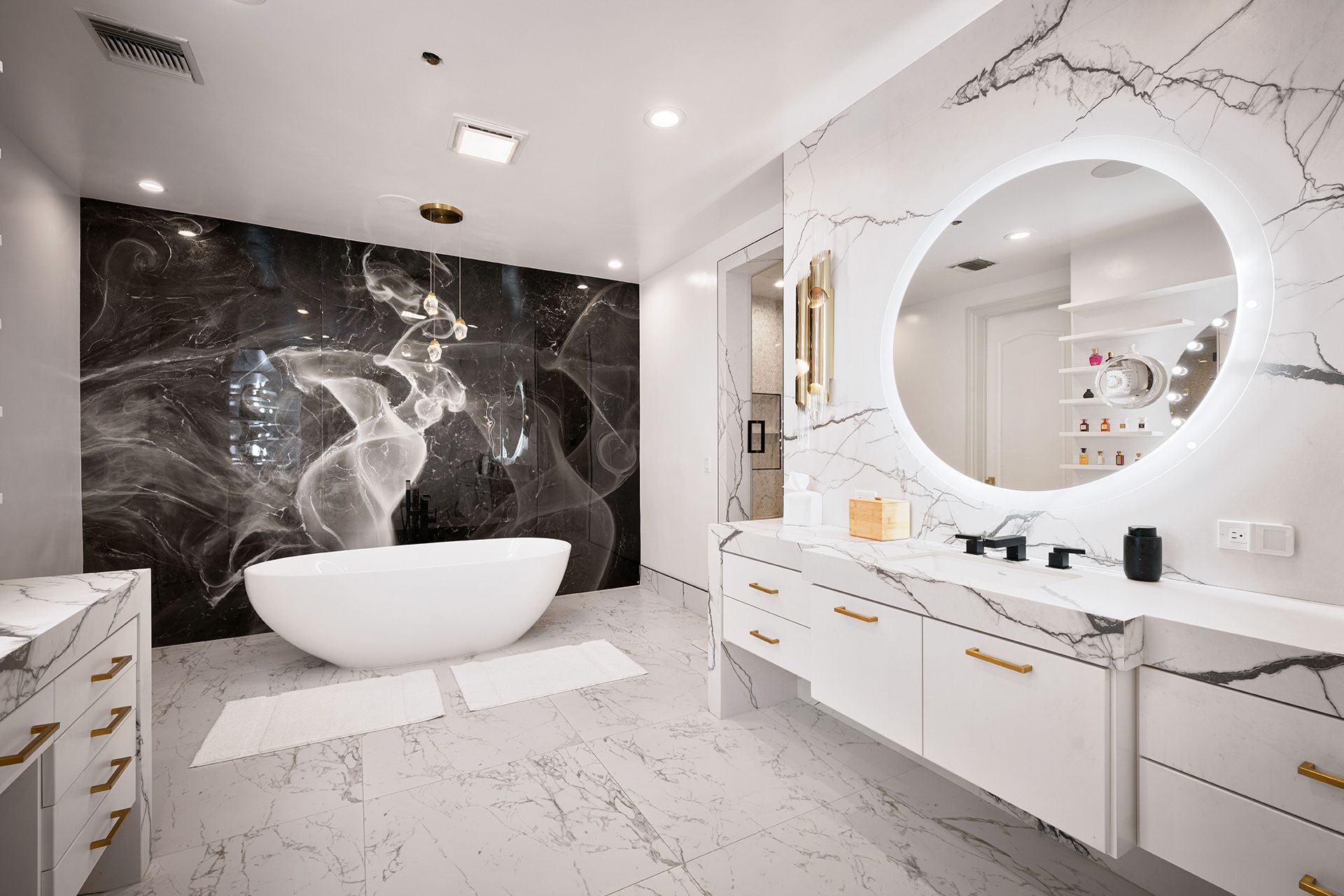 Luxury bathroom with marble accents, a tub, vanity, and a backlit mirror.