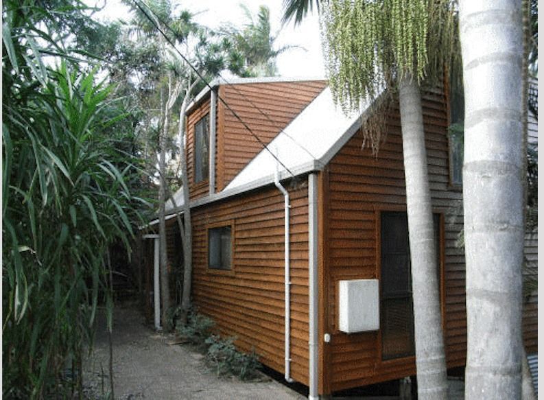 A Wooden House With A White Roof Is Surrounded By Palm Trees — Yves De Wilde Quality Painting Services In Lismore, NSW