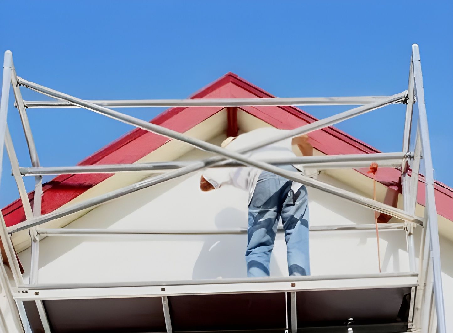 Worker Repainting House Exterior On Scaffold